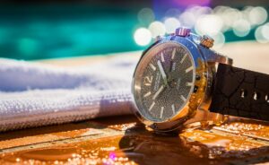 Illustration von einer vermeintlich wasserdichten Armbanduhr im prallen Sonnenschein, die durch UV-Strahlung, Hitze und Chemikalien Schäden erleidet